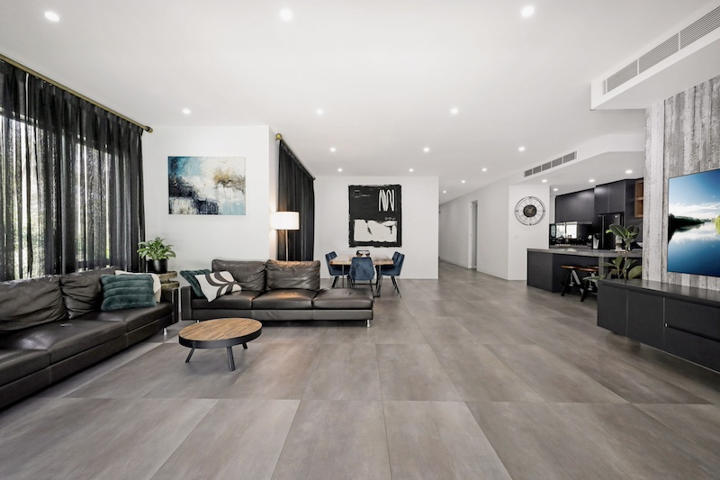 Experience the pinnacle of modern living with this exquisite open-plan living room renovation by Dura Group. As a Sydney-based, family-owned building company, Dura Group specializes in transforming living spaces across the Sutherland Shire, Bayside, Inner West, Georges River, and Randwick regions. This luxurious living area features a seamless blend of contemporary design and functional elegance, boasting premium leather sofas, stylish artwork, and sophisticated lighting fixtures. The chic dining area and state-of-the-art kitchen reflect our commitment to quality and detail. Led by Managing Director Mark, who brings over 27 years of construction experience, Dura Group prioritizes time efficiency, budget-conscious planning, and consistent communication to ensure your renovation journey is smooth and satisfying. Our homeowner-first approach focuses on trust, transparency, and tailored solutions. Transform your space with Dura Group and enjoy a stylish, modern home that perfectly suits your lifestyle. Embark on your renovation journey with us today and elevate your living experience. Contact Dura Group now to start planning your dream home transformation!