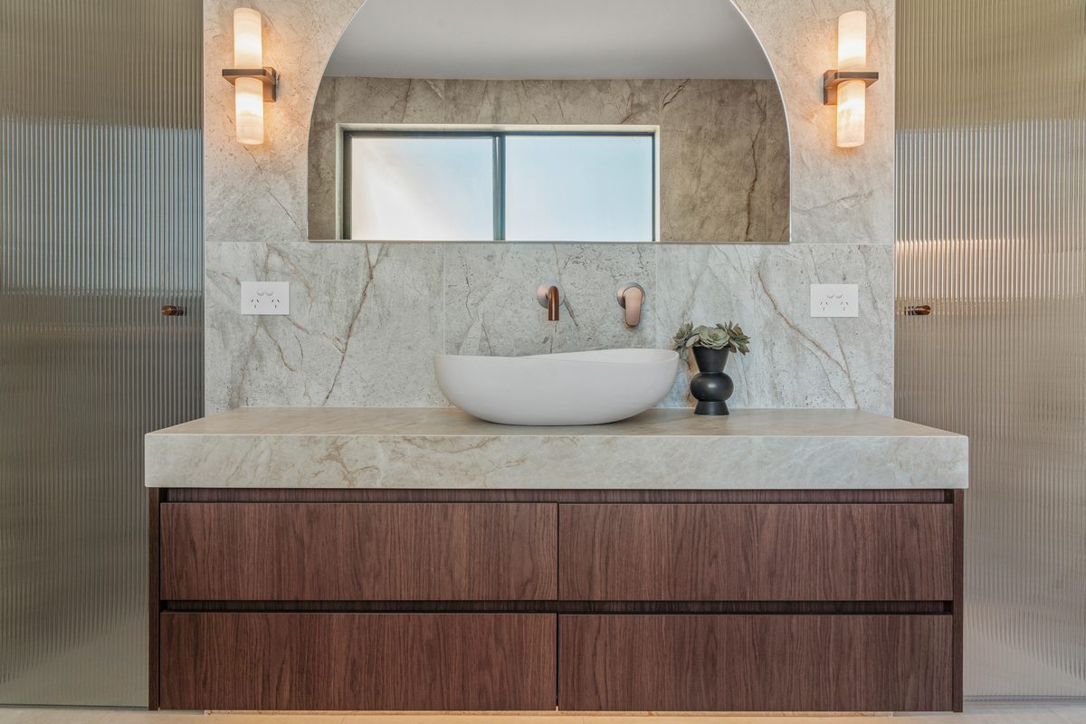 Bathroom renovation with walnut vanity and arched stone alcove
